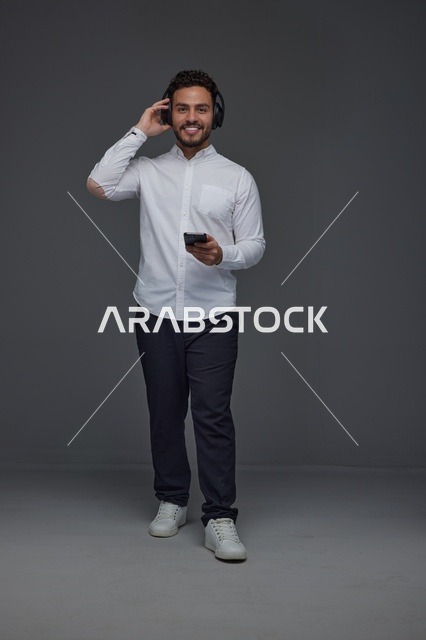 Saudi Man Using Smartphone and Headphones in Studio