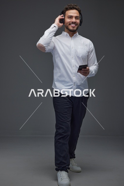 رجل سعودي يستخدم سماعات الرأس والهاتف الذكي