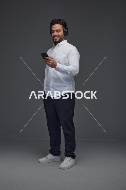 Saudi Man Using Smartphone with Wireless Headphones