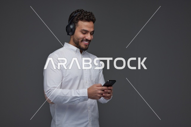 Saudi Man with Headphones Using Smartphone in Studio
