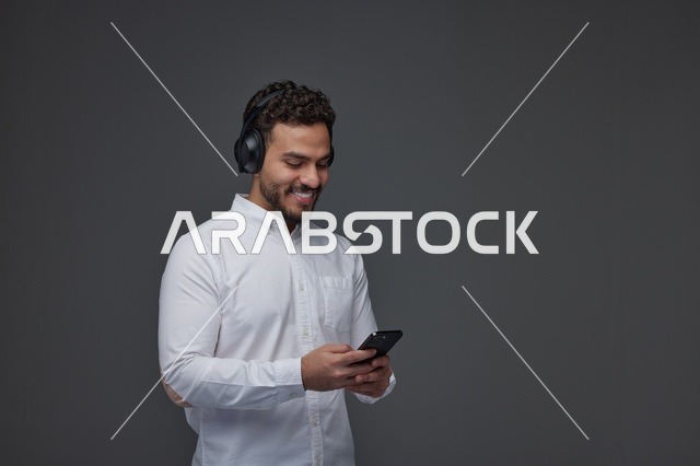 رجل سعودي بسماعات رأس يستخدم الهاتف الذكي في استوديو