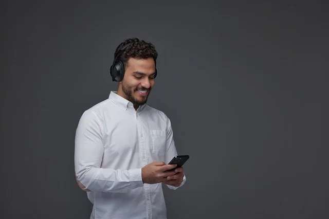 Saudi Man with Headphones Using Smartphone in Studio