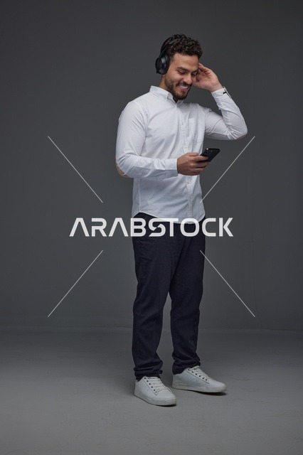 Saudi Man Using Smartphone and Headphones in Studio
