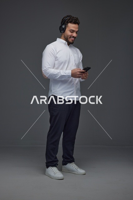 رجل سعودي يستخدم الهاتف الذكي وسماعات الرأس في الاستوديو