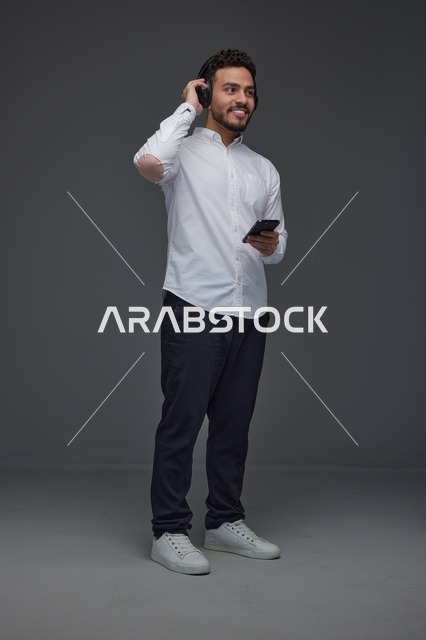 رجل سعودي مع هاتف ذكي وسماعات في الاستوديو