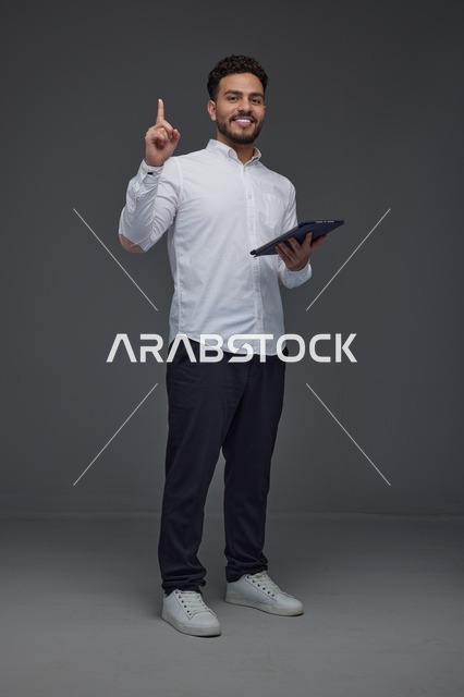 Smiling Saudi Man Holding Tablet Pointing Upwards