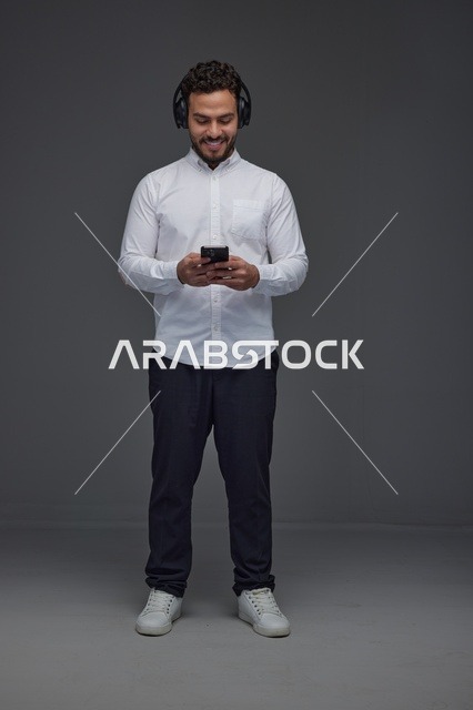 رجل سعودي يستخدم سماعات الرأس وهاتف ذكي في الاستوديو