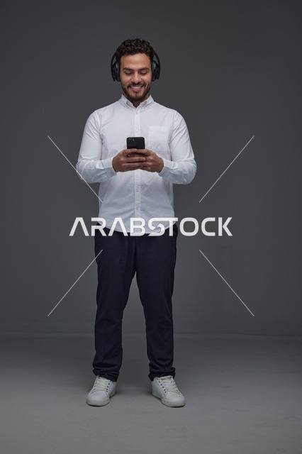 Saudi Man Using Smartphone with Wireless Headphones