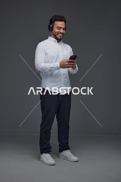 Saudi Man Using Smartphone with Headphones in Studio