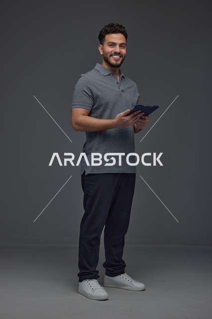 رجل سعودي يحمل جهازًا لوحيًا في الاستوديو