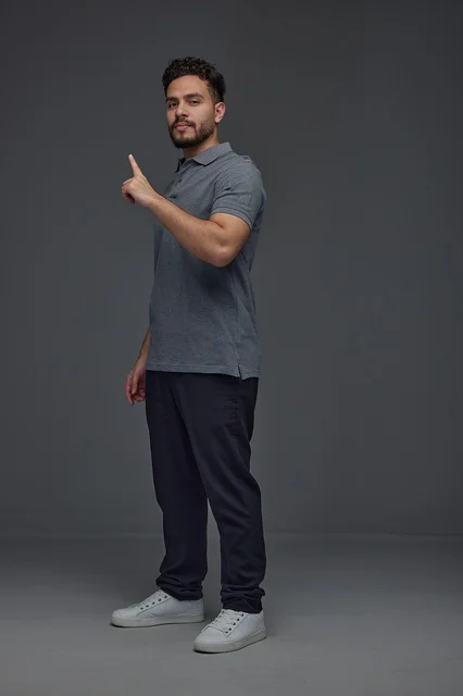 Saudi Man Pointing Upward on Grey Studio Background