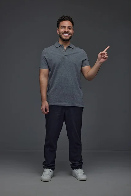 Saudi Man Smiling and Pointing Finger on Gray Background