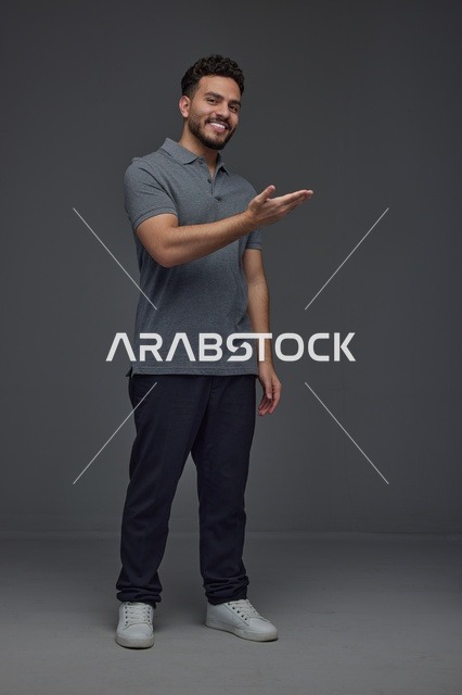 Smiling Saudi Man Presenting on Solid Grey Background