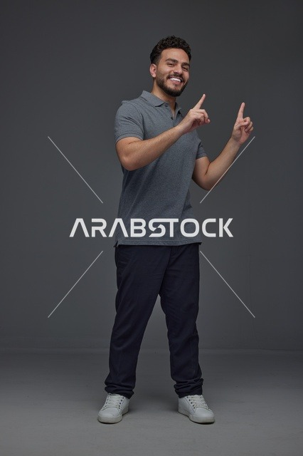 Smiling Saudi Man Pointing Up on Grey Background