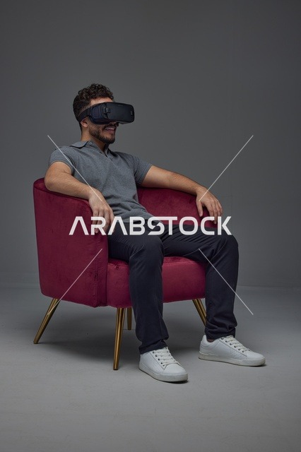 Saudi Man Using Virtual Reality Headset on Red Armchair