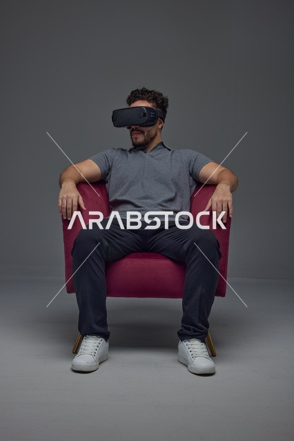 رجل سعودي يرتدي نظارة الواقع الافتراضي ويجلس على كرسي
