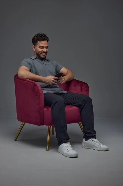 Saudi Man Using Smartphone in Red Armchair Studio
