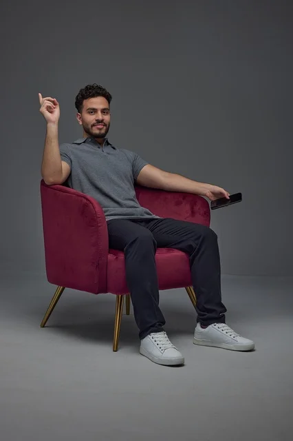 Saudi Man on Armchair Holding Smartphone Studio Shot