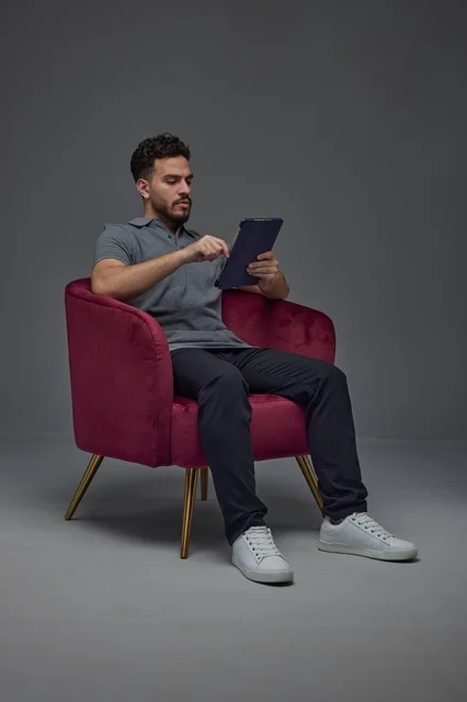 Saudi Man Using Tablet in Red Armchair Studio Shot