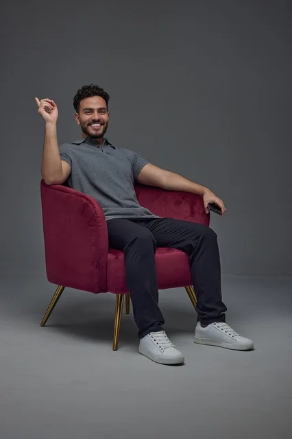Smiling Saudi Man Sitting in Burgundy Velvet Armchair