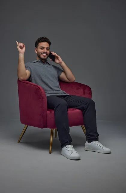 Saudi Man on Smartphone in Armchair Studio Setting