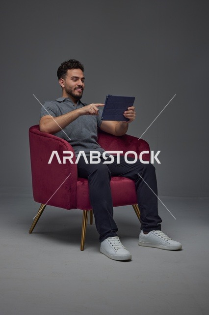 Saudi Man Using Digital Tablet in Studio Armchair