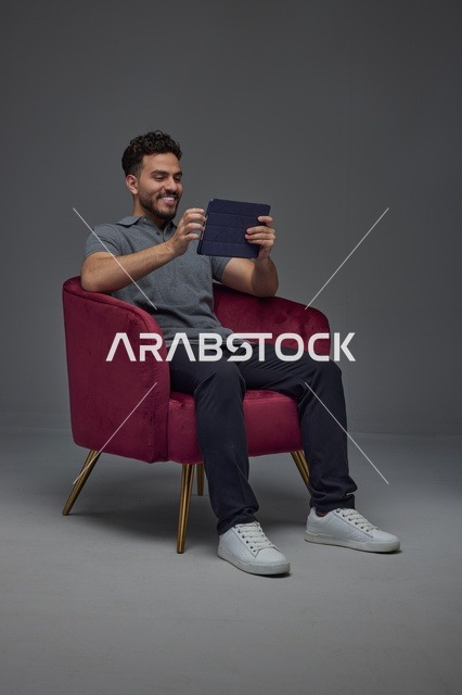 Man Sitting in Armchair Using Digital Tablet