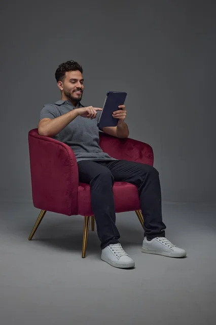 Saudi Man Using Digital Tablet in Red Armchair Studio