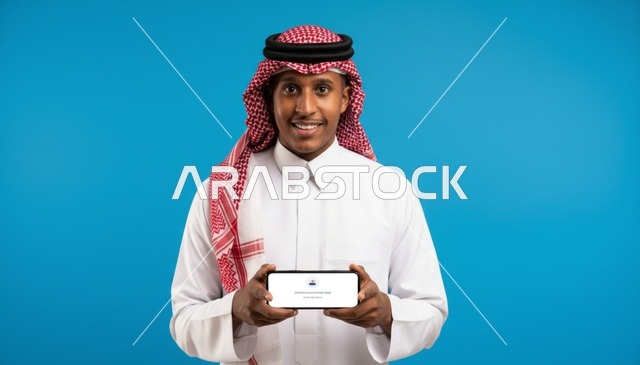 رجل سعودي يحمل هاتف ذكي خلفية زرقاء