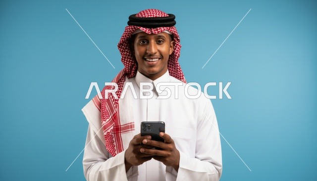 رجل سعودي يحمل هاتفاً ذكياً على خلفية زرقاء