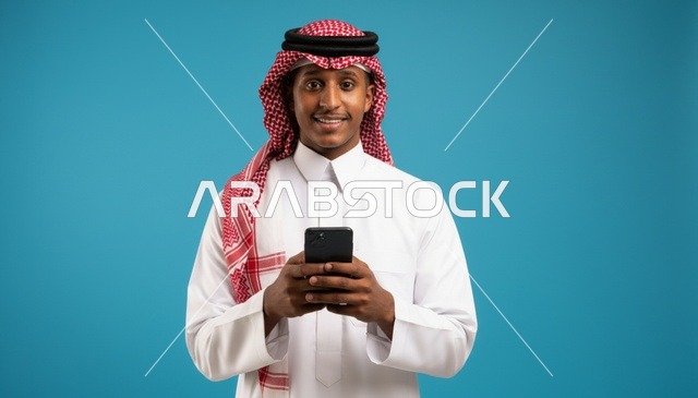 رجل سعودي يمسك هاتفاً ذكياً خلفية زرقاء