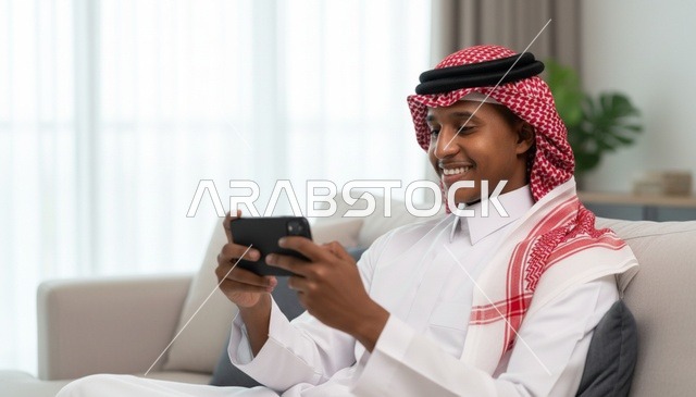 رجل سعودي يستخدم الهاتف الذكي في غرفة المعيشة