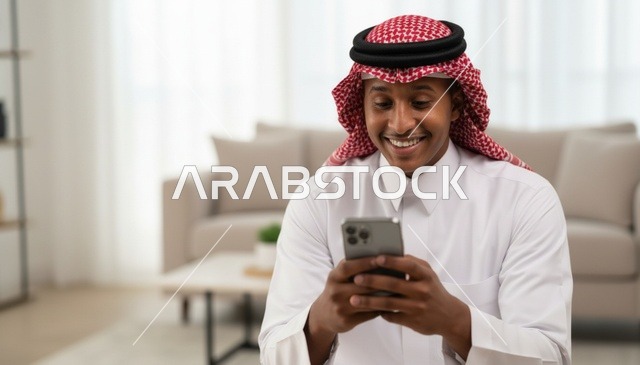 رجل سعودي يستخدم الهاتف الذكي بالزي التقليدي
