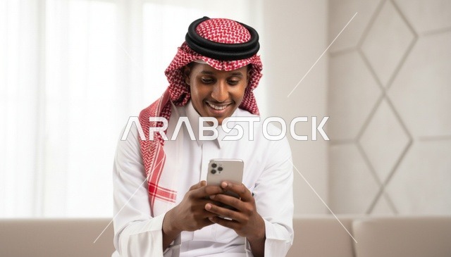 رجل سعودي يستخدم الهاتف الذكي بالزي التقليدي