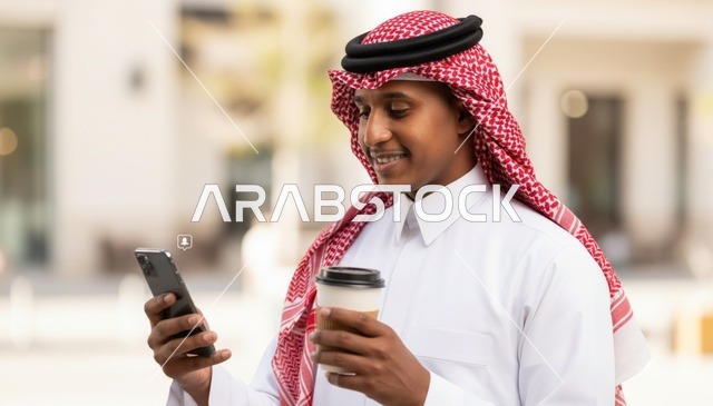 رجل سعودي بالثوب التقليدي يستخدم الهاتف الذكي