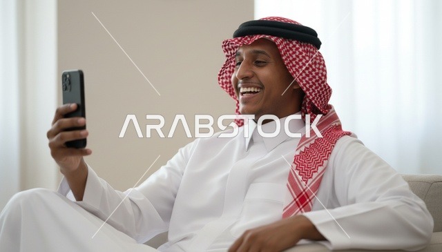 رجل سعودي بالزي التقليدي يستخدم الهاتف الذكي