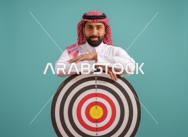رجل سعودي يرتدي الثوب مع لوحة أهداف لتحقيق النجاح