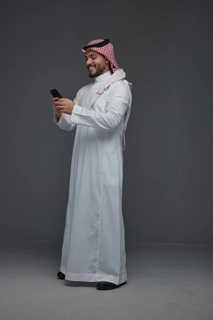 Saudi Man in Traditional Thobe Using Smartphone