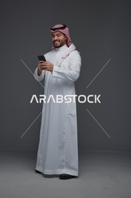 رجل سعودي يستخدم الهاتف الذكي بالزي التقليدي