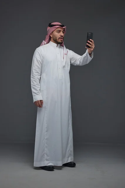 رجل سعودي بالثوب التقليدي يلتقط سيلفي بالهاتف الذكي