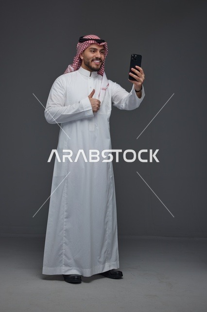رجل سعودي يلتقط صورة سيلفي بالهاتف الذكي في الاستوديو