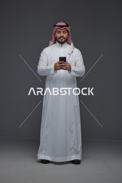 رجل سعودي يستخدم الهاتف الذكي بالزي التقليدي