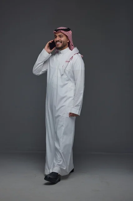 رجل سعودي بالزي التقليدي يتحدث عبر الهاتف الذكي