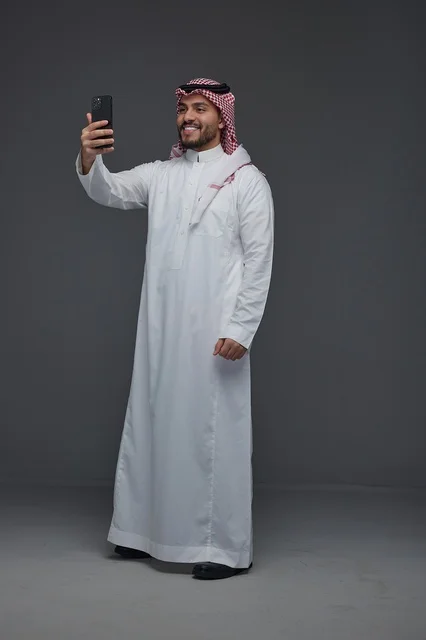 رجل سعودي بالثوب التقليدي يلتقط صورة سيلفي بالجوال