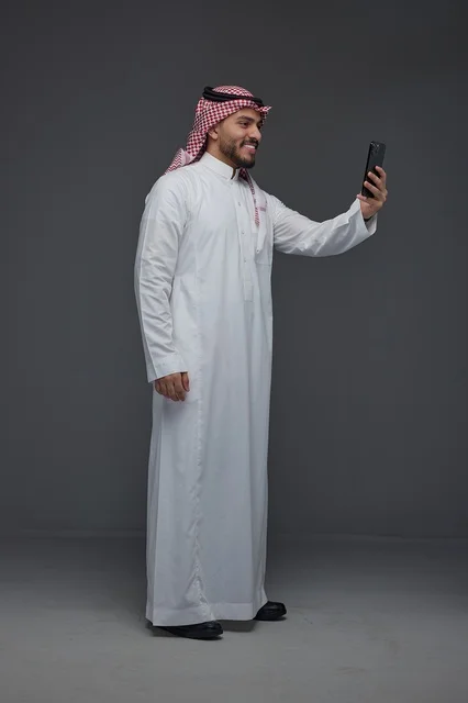 رجل سعودي بالزي التقليدي يلتقط صورة سيلفي بالجوال