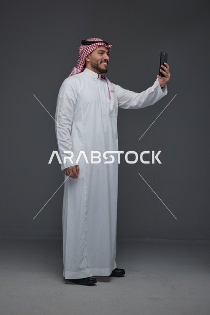 رجل سعودي يلتقط صورة سيلفي بالهاتف الذكي في الاستوديو