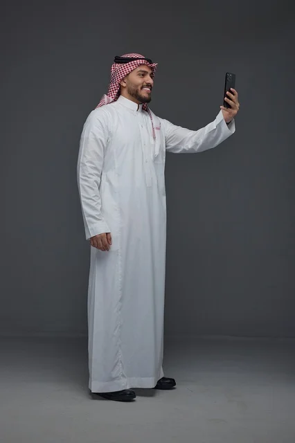 Saudi Man Taking Selfie with Smartphone in Grey Studio