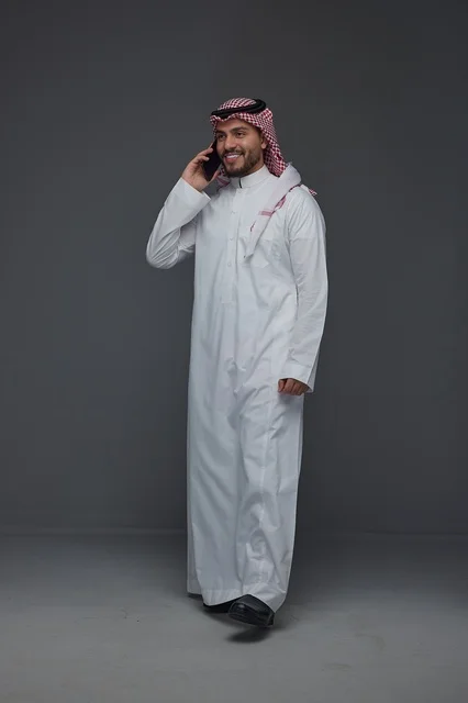 Saudi Man in Traditional Thobe Talking on Smartphone