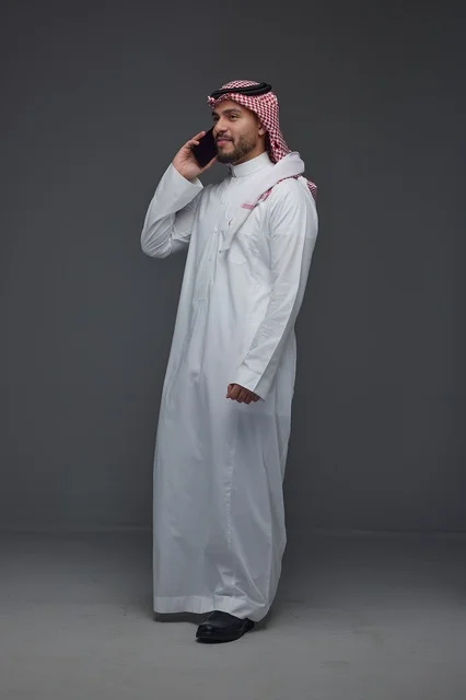 رجل سعودي بالزي التقليدي يتحدث عبر الهاتف الذكي