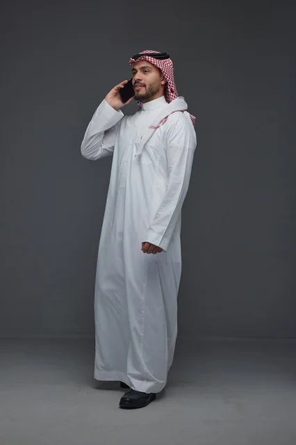 Saudi Man in Traditional Thobe Using Smartphone
